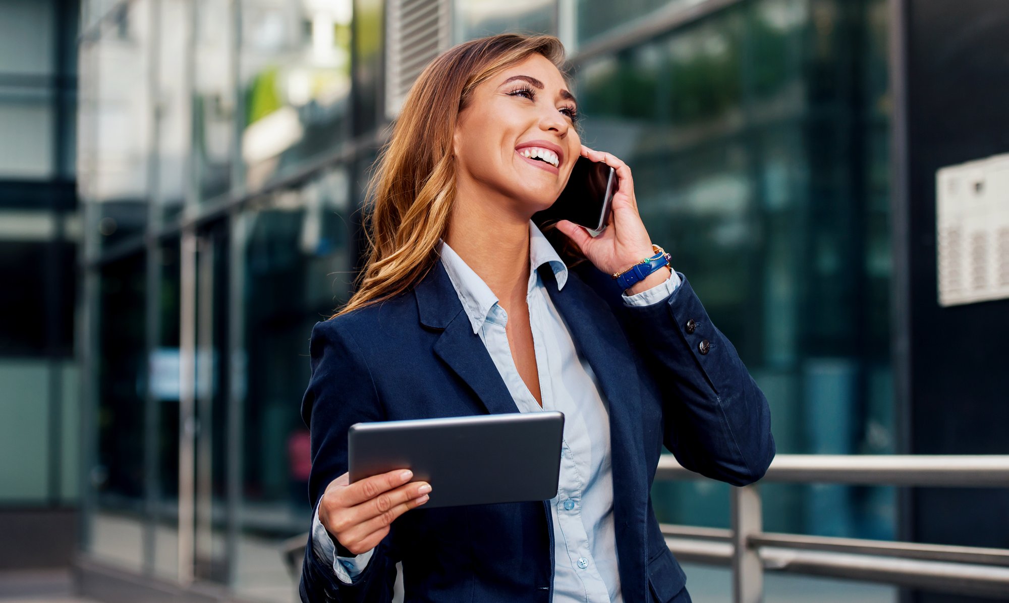 Businesswoman holding tablet and making a phone call in front of the corporation. Business, lifestyle concept Businesswoman holding tablet and making a phone call in front of the corporation. Business, lifestyle concept